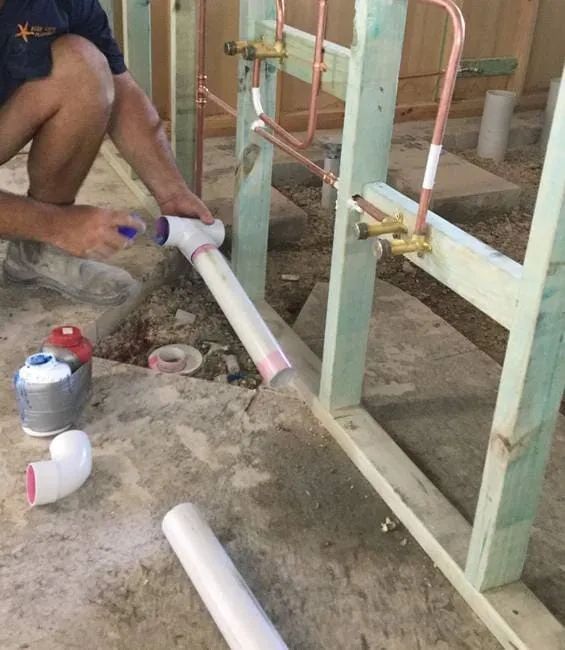 Plumber gluing PVC pipe on new build in Gladstone
