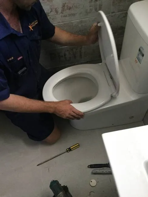 Plumber installing new toilet bowl in Gladstone
